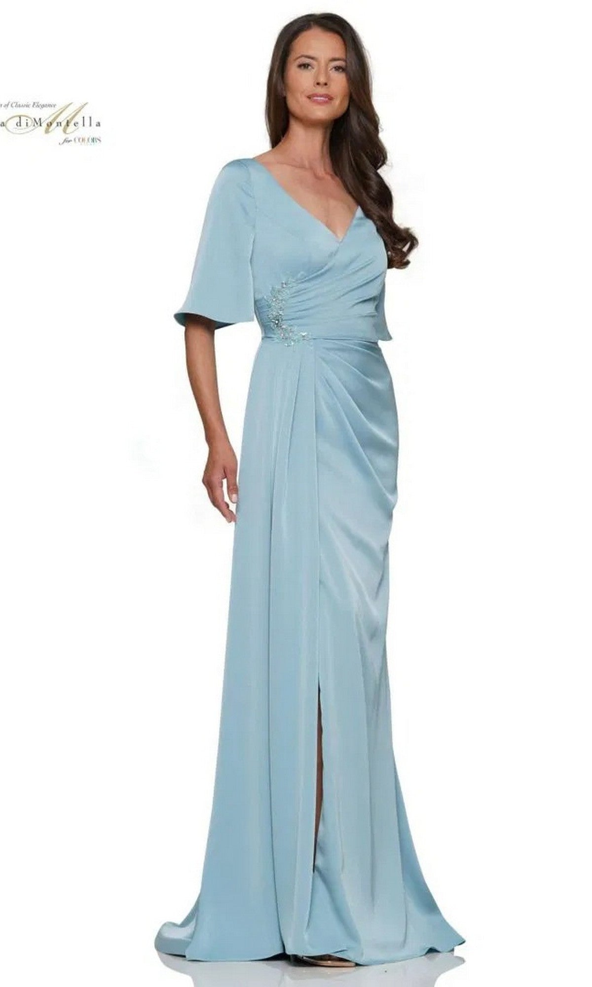 A woman in the Rina Di Montella RD2974 long formal dress in seafoam, featuring short flutter sleeves, V-neckline, ruched bodice, and front slit, stands against a plain white background.